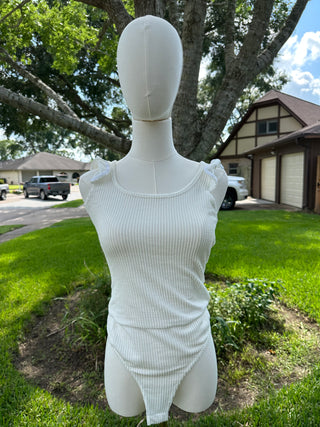 Mannequin wearing a white ribbed body suit in a suburban setting