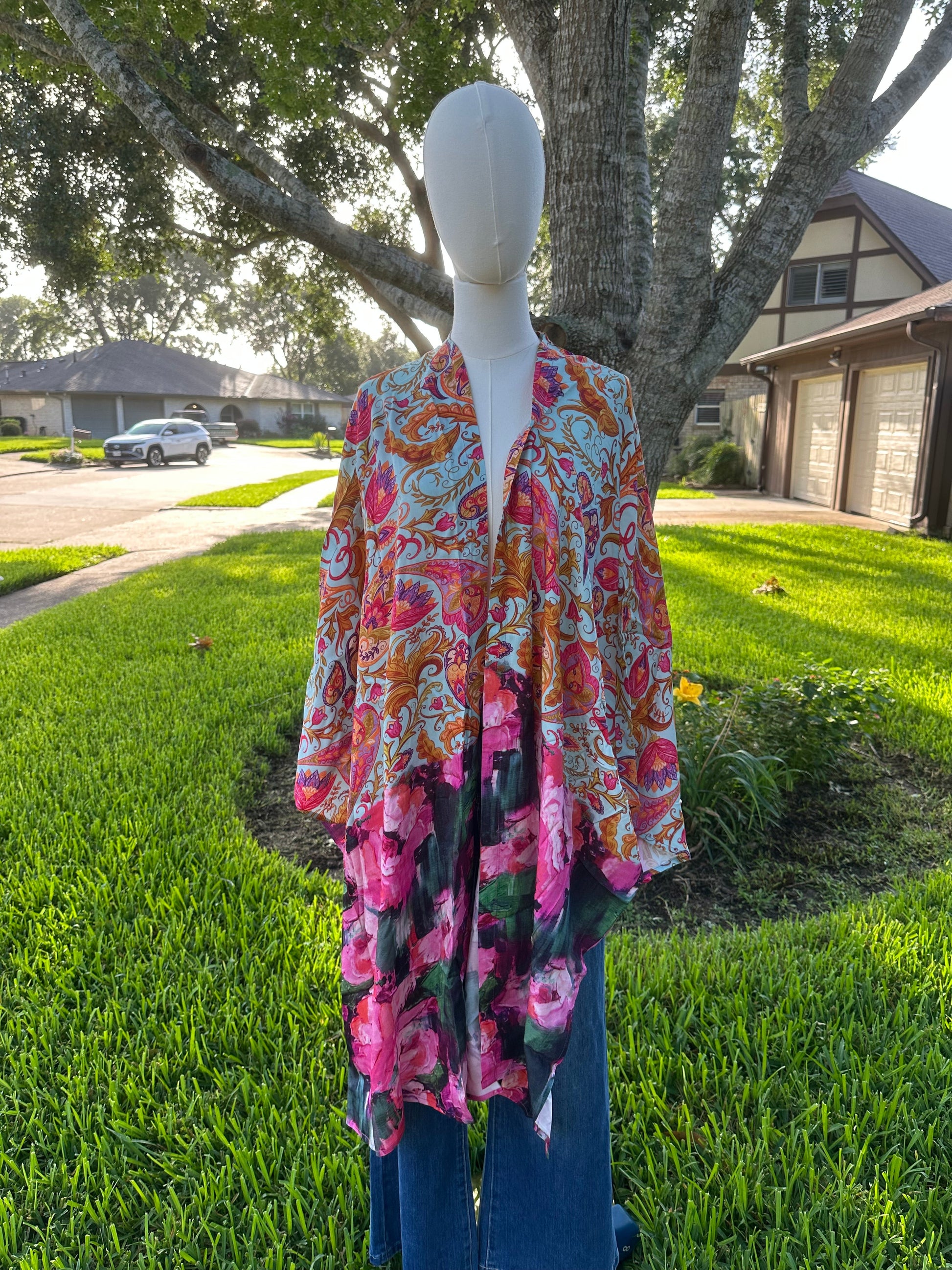 Mannequin wearing a colorful floral kimono in a grassy outdoor setting