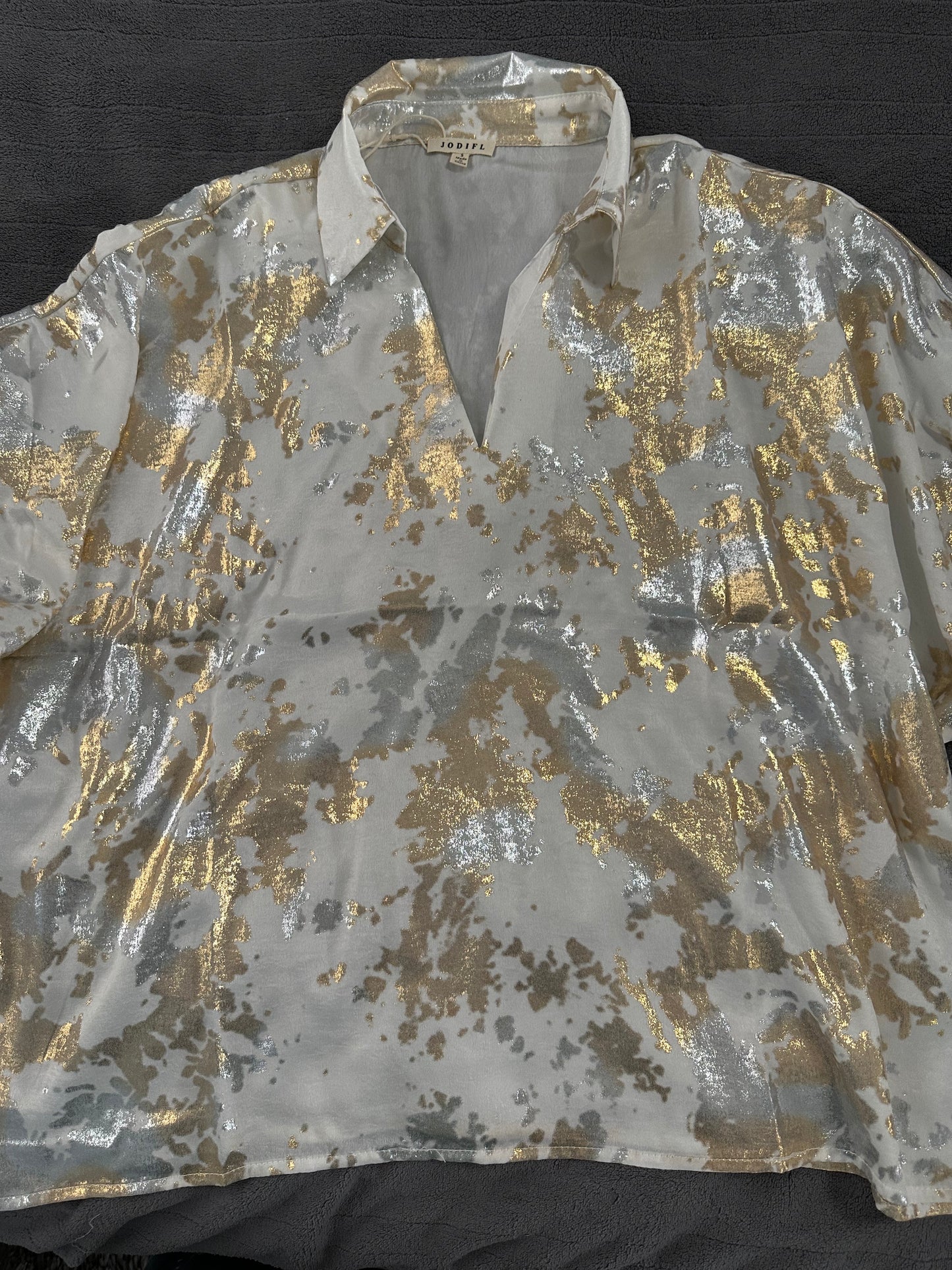 Shiny gold and silver patterned shirt on a black background