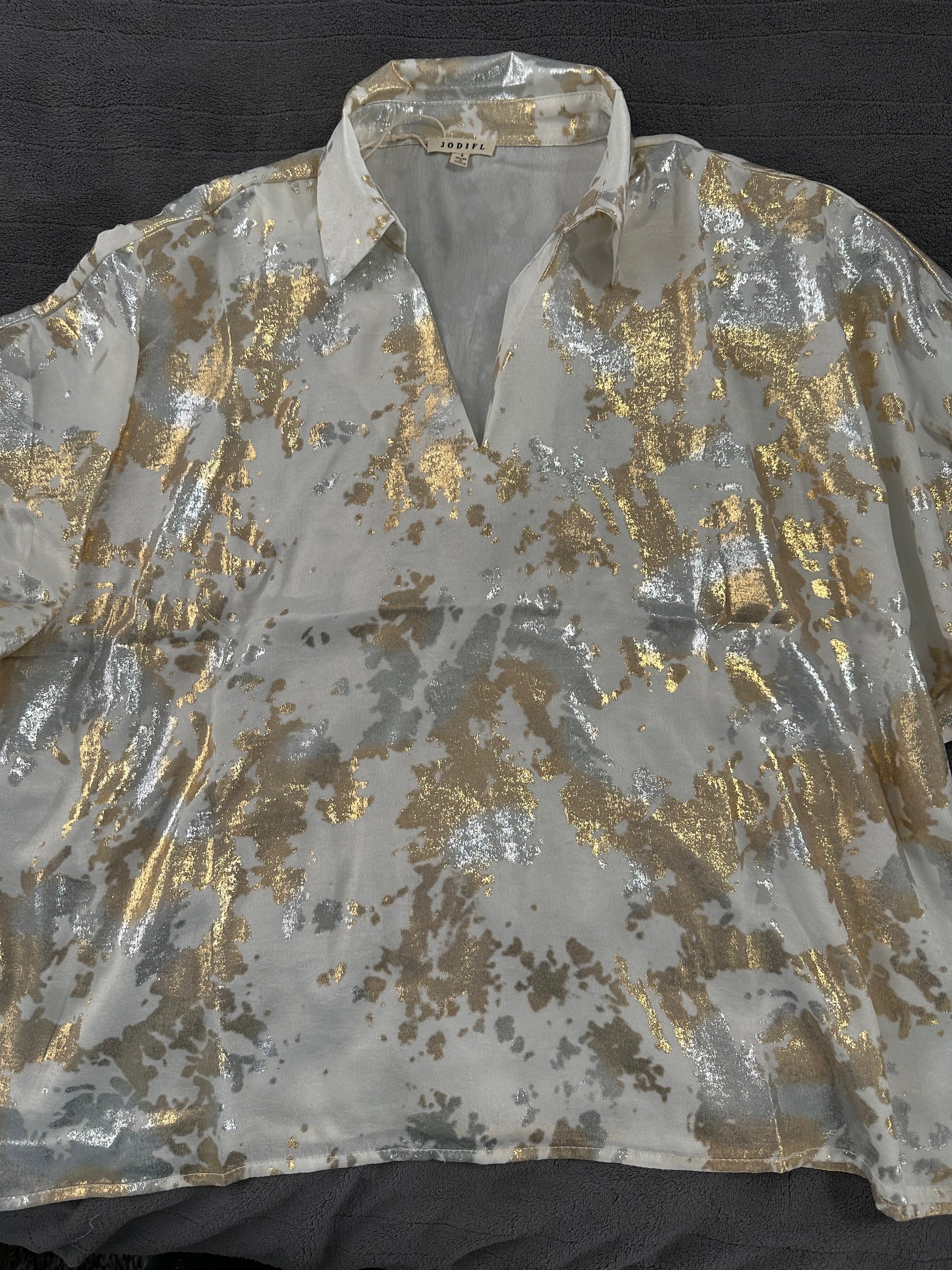 Shiny gold and silver patterned shirt on a black background