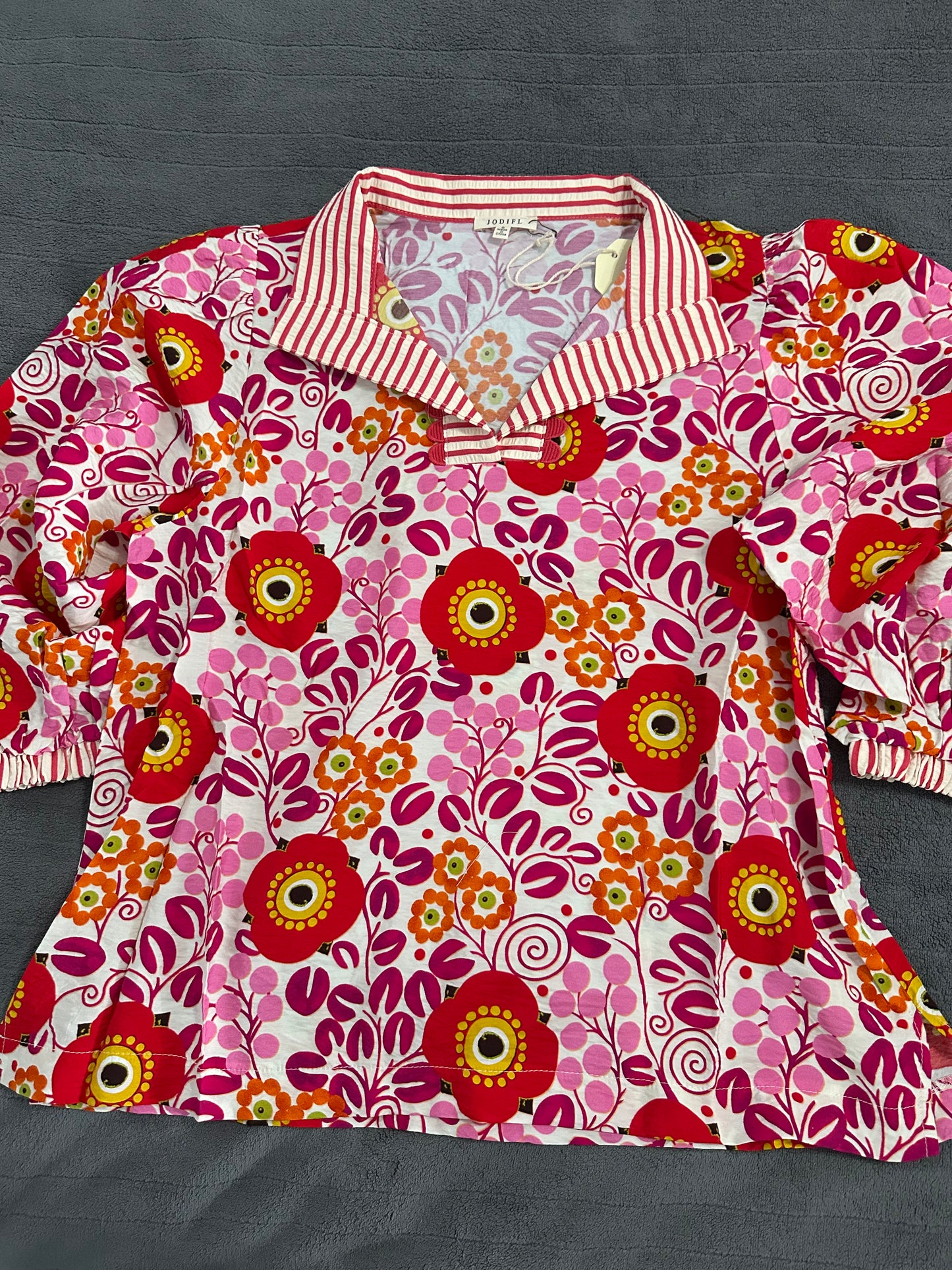 Floral patterned shirt with a red and white striped collar on a dark background