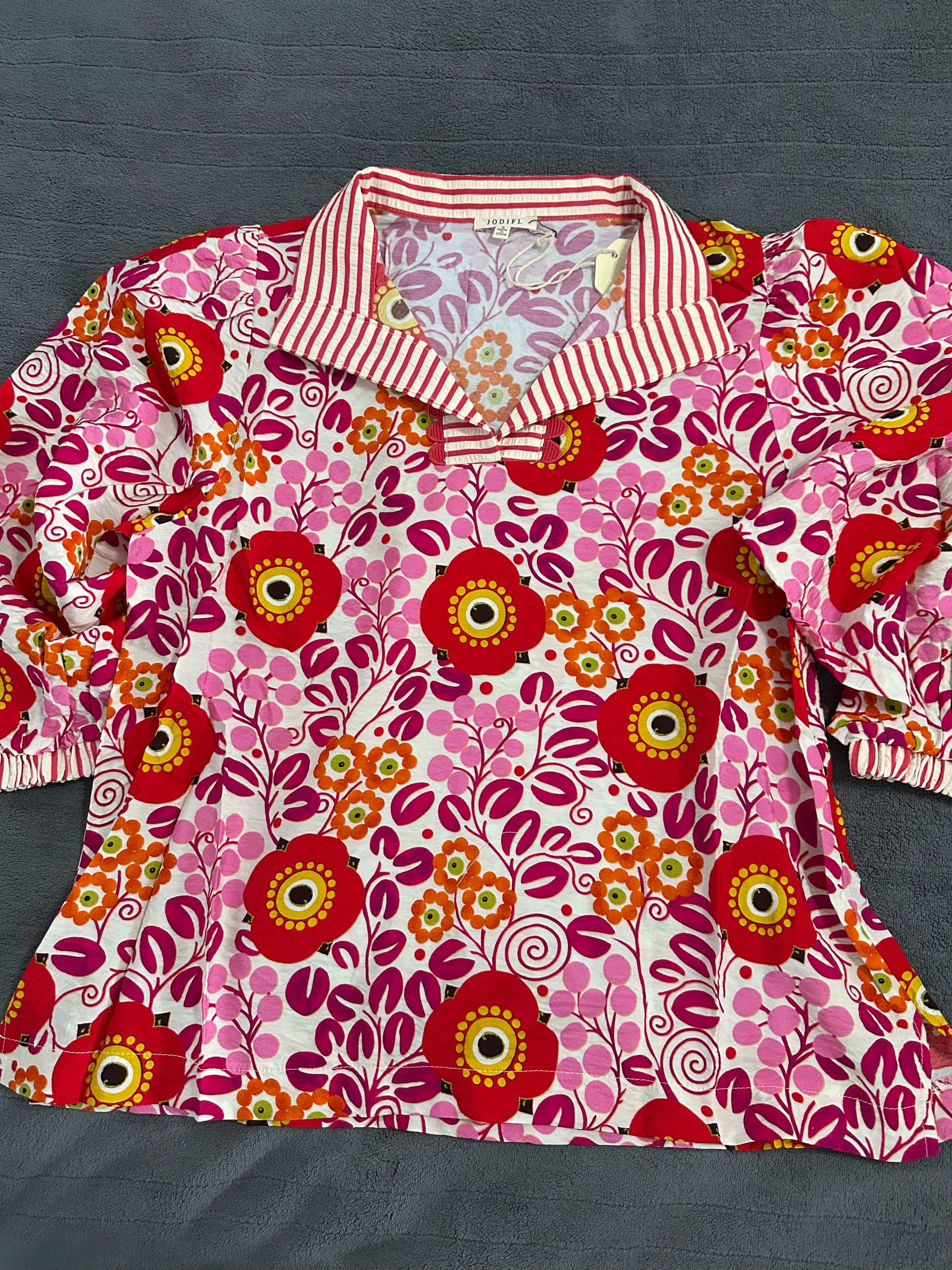 Floral patterned shirt with a red and white striped collar on a dark background
